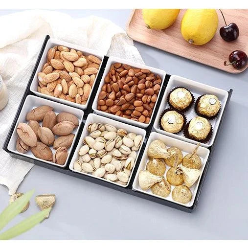 Premium British plastic snack trays in a variety of colours, including clear, white, and grey, with a black, white, or natural wood pallet for storage and display.