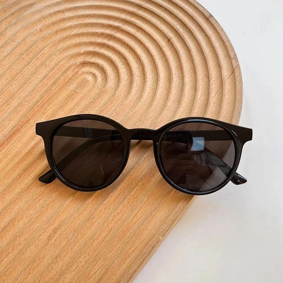 A pair of stylish, retro-inspired round sunglasses with a white frame, providing UV protection and a chic, contemporary look.