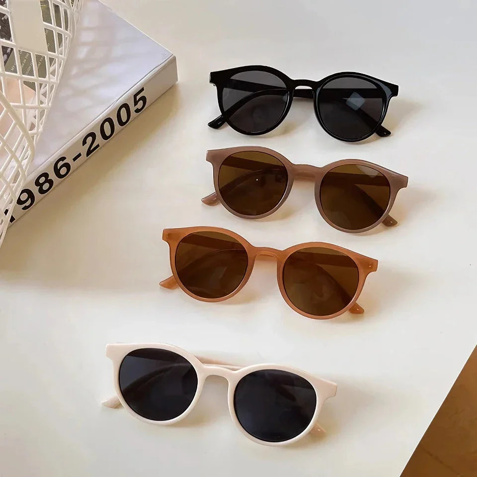 A pair of stylish, retro-inspired round sunglasses with a white frame, providing UV protection and a chic, contemporary look.