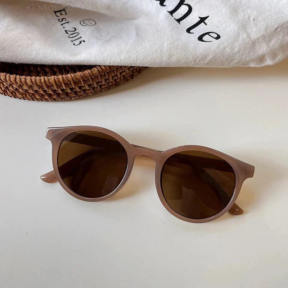 A pair of stylish, retro-inspired round sunglasses with a white frame, providing UV protection and a chic, contemporary look.