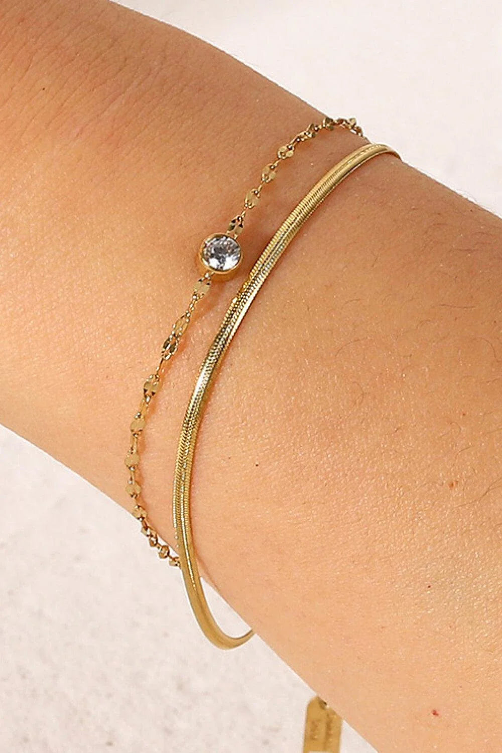 Close-up of a gold-coloured double-layered bracelet with sparkling rhinestones, on a white background.