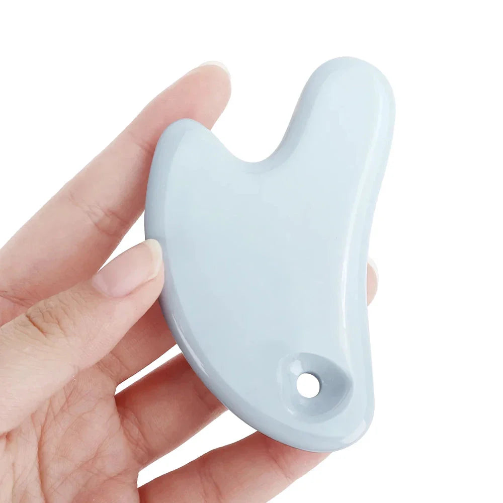 Ceramic Gua Sha facial massager in blue, pink, and white colours, designed to improve circulation and promote lymphatic drainage for radiant, youthful skin.