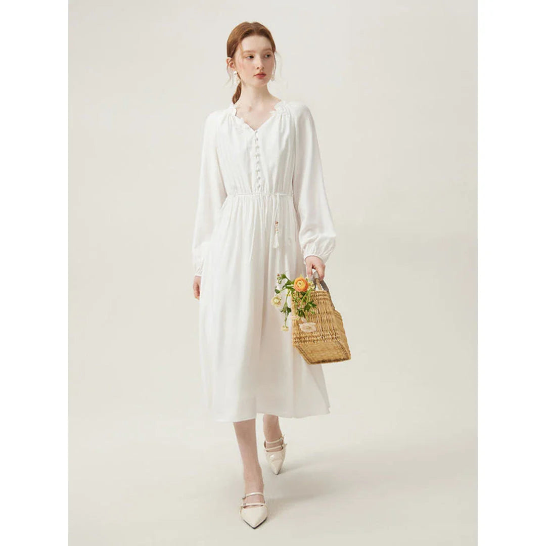 A woman wearing a long-sleeved, midi-length dress in a French pastoral style with an empire waistline and A-line silhouette.