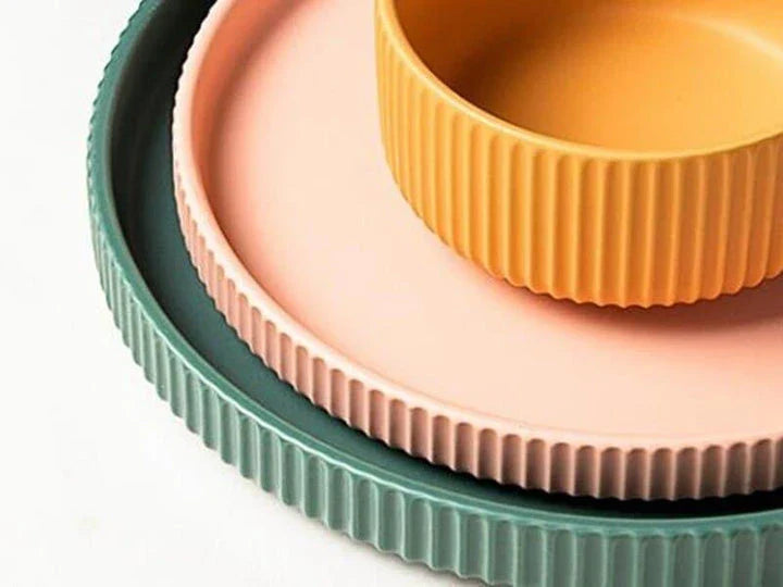 Candy-coloured ribbed ceramic tableware featuring plates, bowls, and other dining accessories in vibrant hues