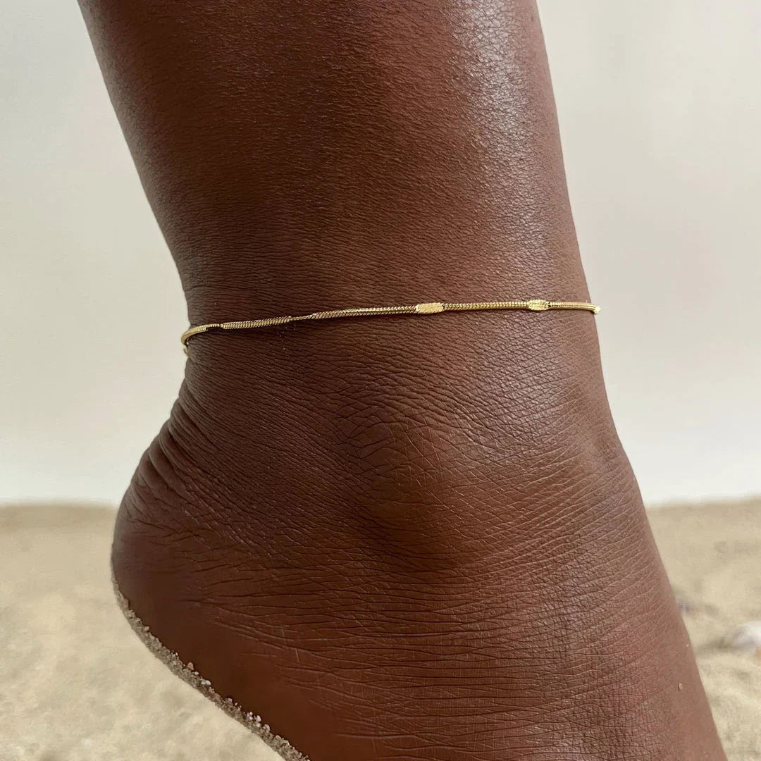 Elegant gold stainless steel minimalist anklet with delicate charm, adjustable length, and durable construction