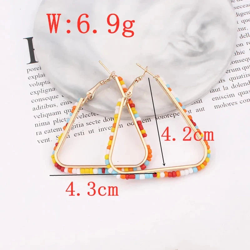 Colourful beaded triangle hoop earrings in gold metal with vibrant beadwork
