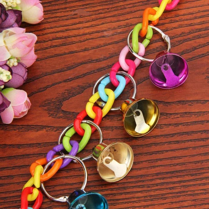 Acrylic bird bells swing with intricate design, hanging in a lush garden setting