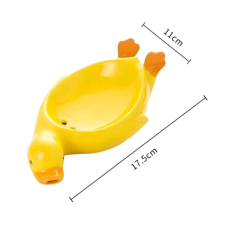 A yellow duck-shaped ceramic soap dish with a drainage system, suitable for modern and traditional British bathrooms.