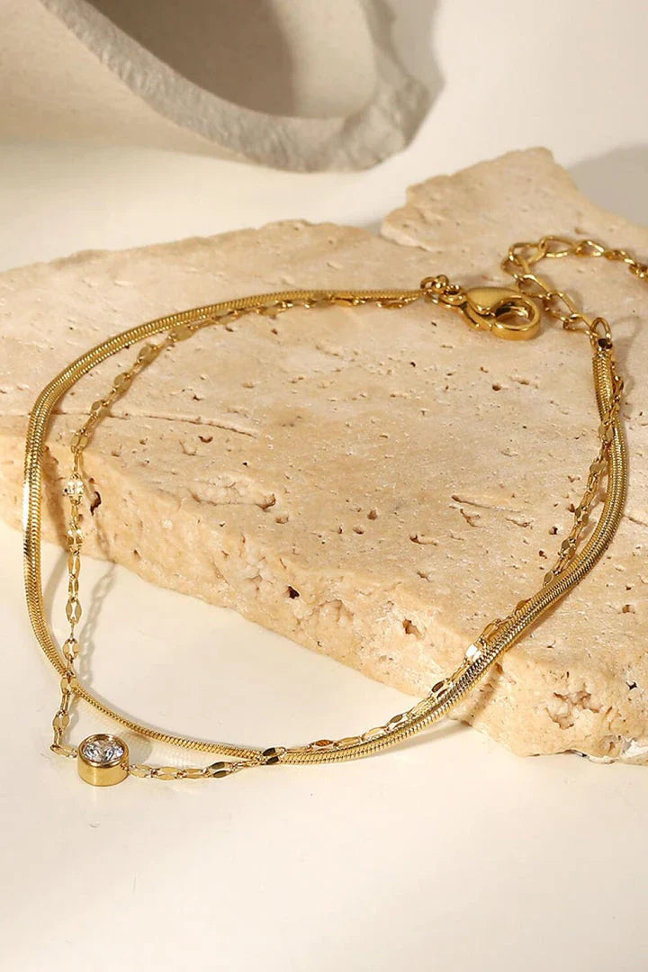Close-up of a gold-coloured double-layered bracelet with sparkling rhinestones, on a white background.