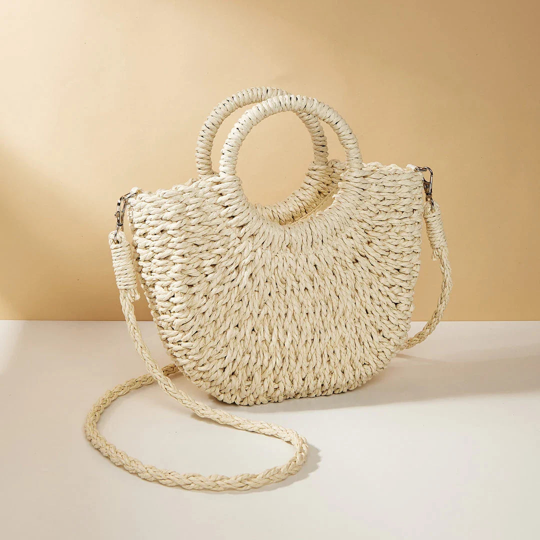 Stylish straw woven women's beach shoulder bag in a half-moon shape, featuring a cotton lining and string closure for a minimalist, bohemian-inspired look.