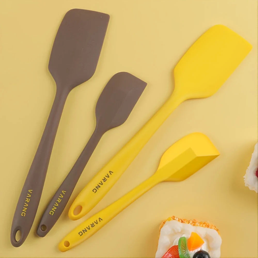 A set of two high-quality silicone spatulas in brown and yellow colours, designed for versatile cooking and baking tasks.