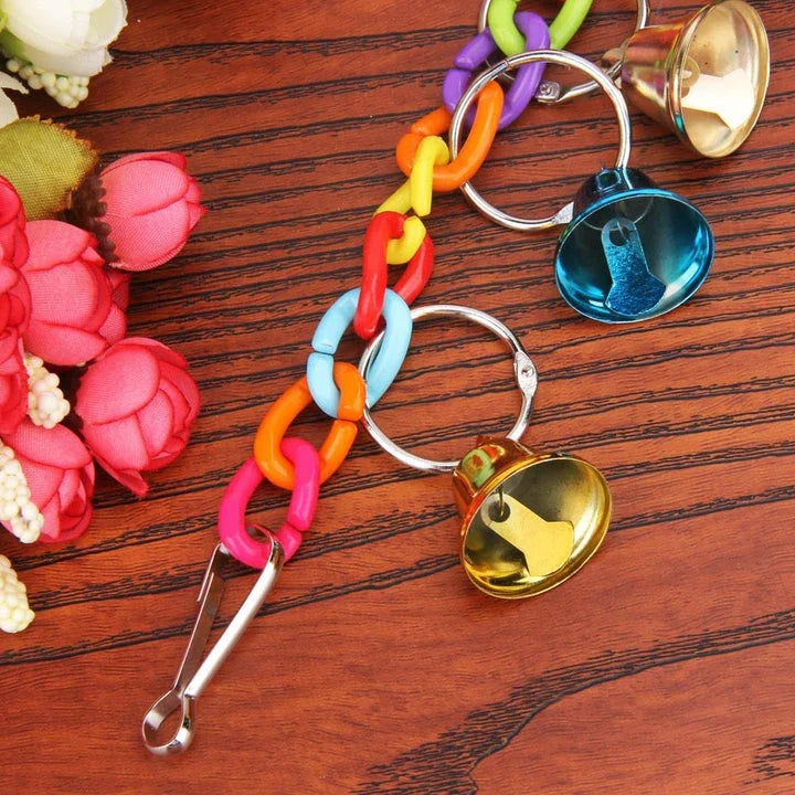 Acrylic bird bells swing with intricate design, hanging in a lush garden setting