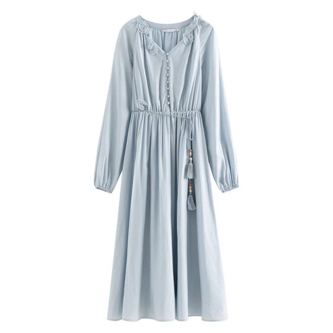 A woman wearing a long-sleeved, midi-length dress in a French pastoral style with an empire waistline and A-line silhouette.