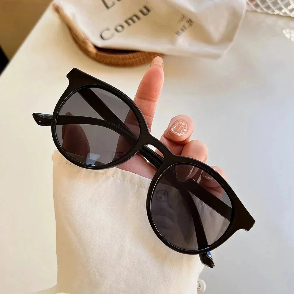 A pair of stylish, retro-inspired round sunglasses with a white frame, providing UV protection and a chic, contemporary look.
