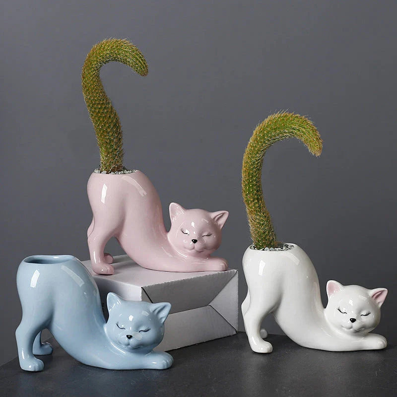 A white ceramic flower pot with a playful cartoon cat design and a functional tail element, perfect for desktops and small spaces.