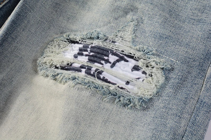 Stylish ripped denim jeans with a unique black and white patch design, perfect for British gentlemen