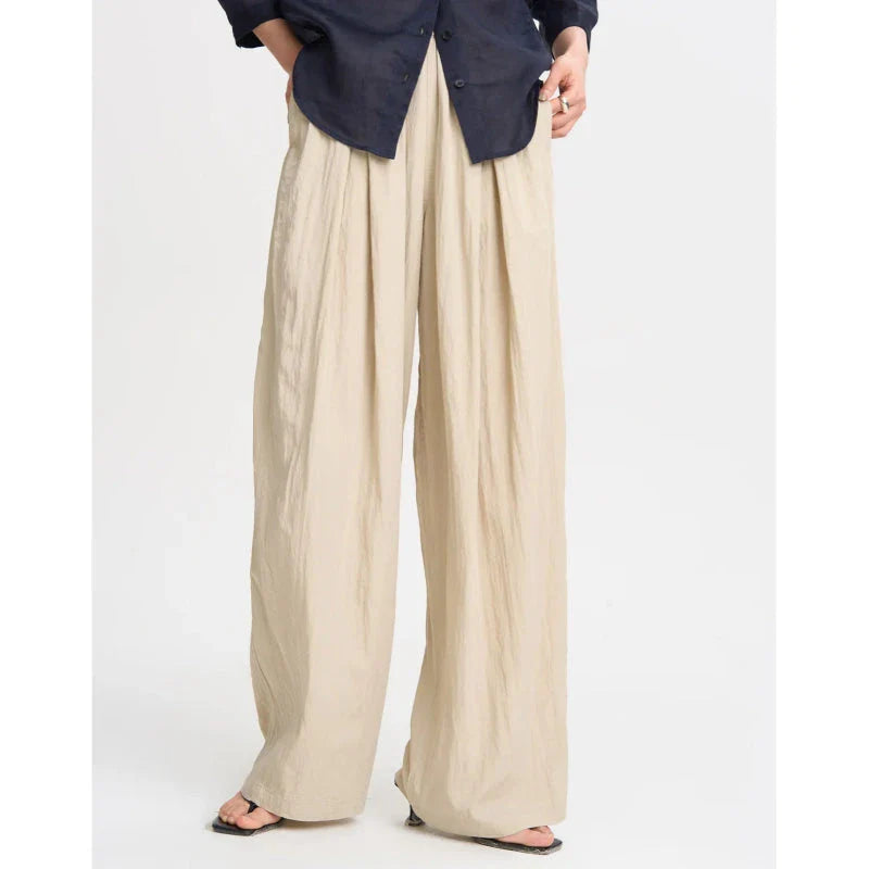 Pleated wide-leg high-waisted trousers in a herringbone plaid pattern, featuring a flattering silhouette and comfortable cotton-linen blend