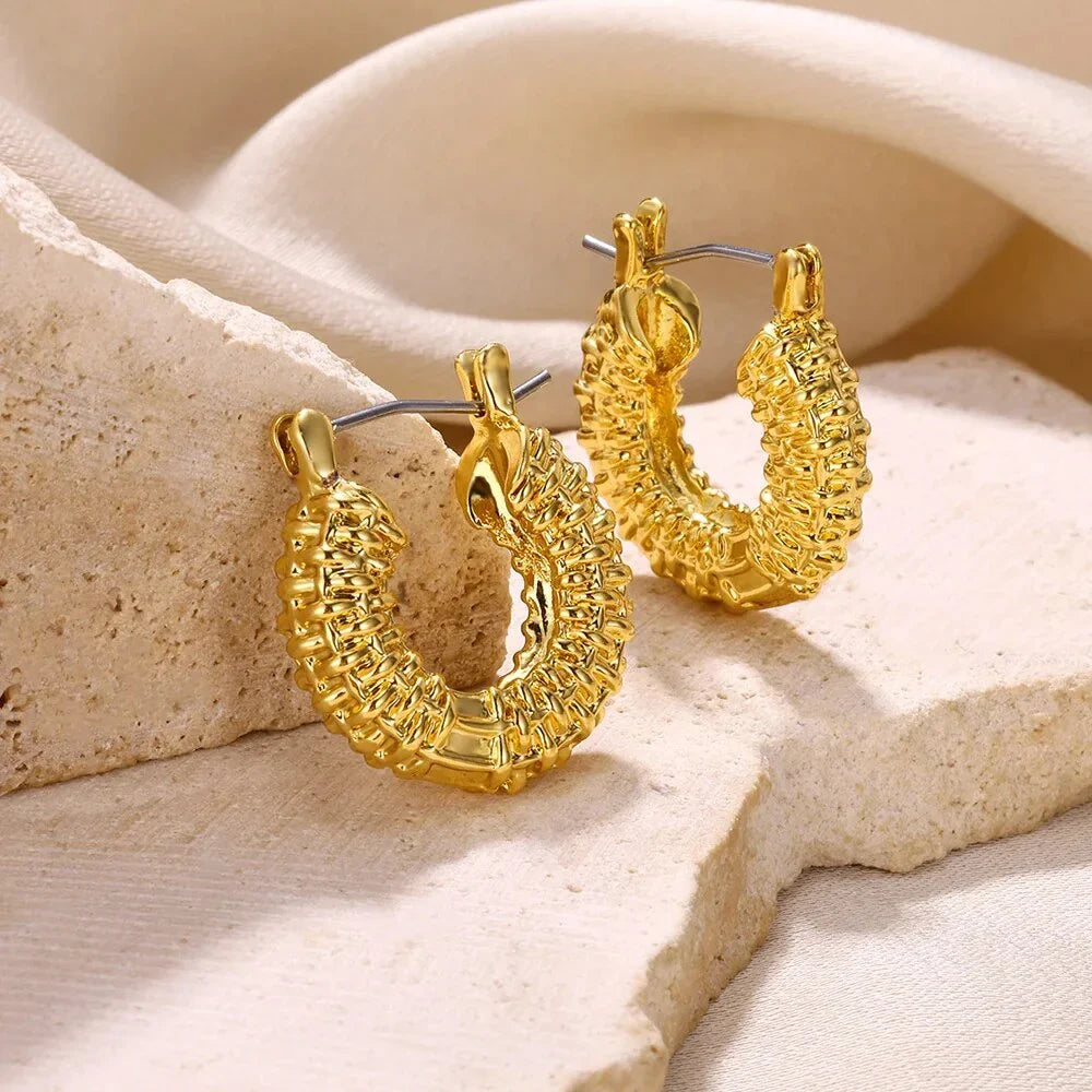 A pair of gold-toned stainless steel hoop earrings, showcasing a classic and sophisticated design