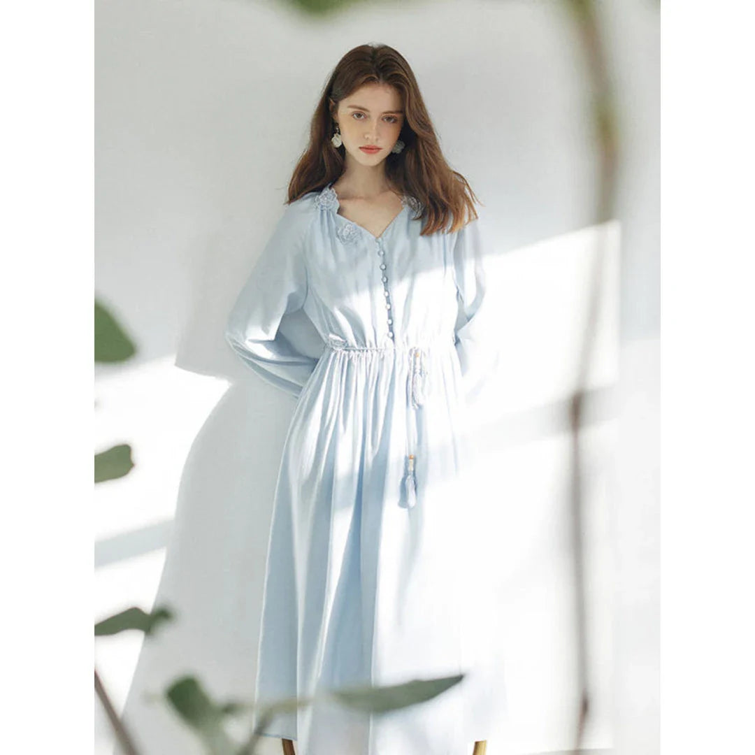 A woman wearing a long-sleeved, midi-length dress in a French pastoral style with an empire waistline and A-line silhouette.