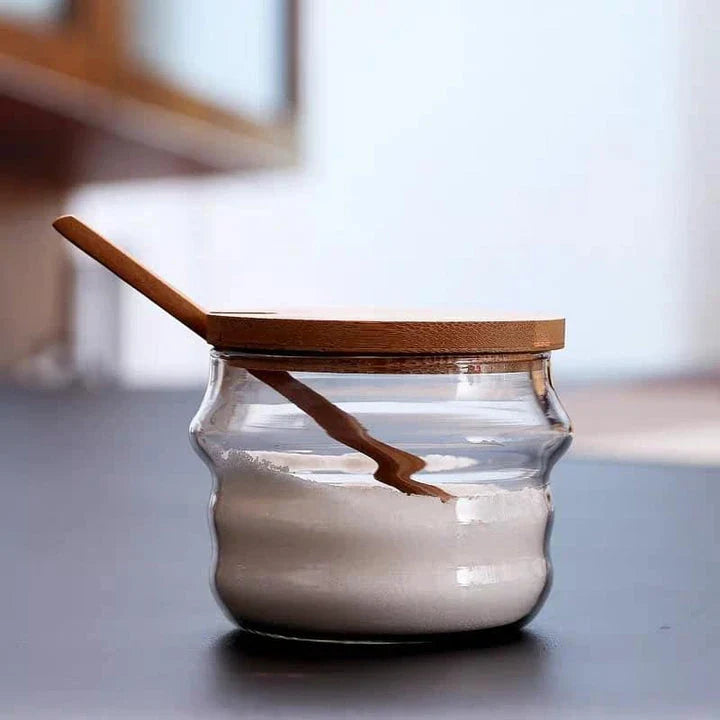 Elegant glass canister with wooden spoon, a versatile kitchen accessory for storing and displaying pantry items