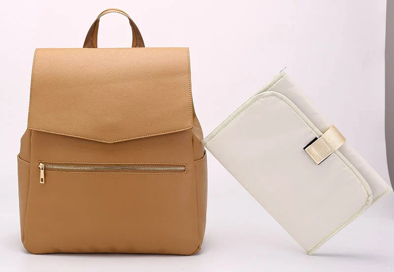 A stylish and practical PU leather mummy bag with a large capacity, multiple pockets, and included accessories like a changing pad and stroller hooks.