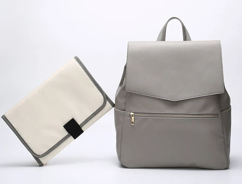 A stylish and practical PU leather mummy bag with a large capacity, multiple pockets, and included accessories like a changing pad and stroller hooks.