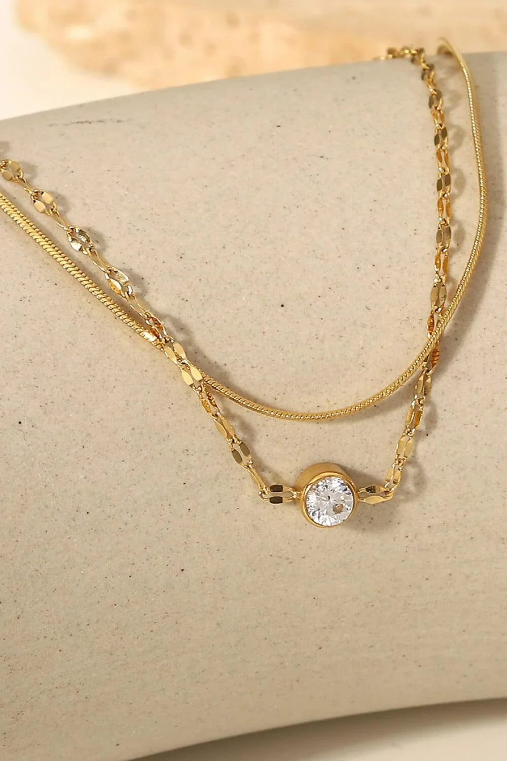 Close-up of a gold-coloured double-layered bracelet with sparkling rhinestones, on a white background.