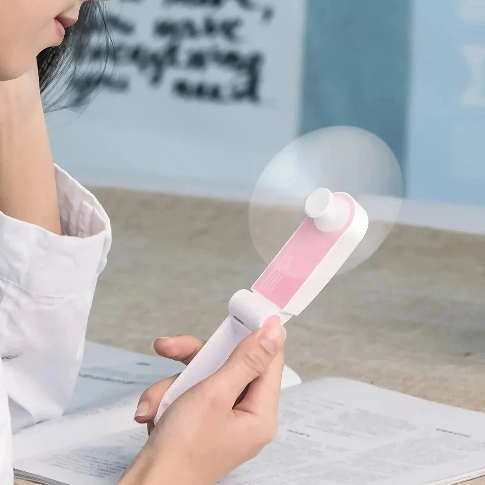 Compact rechargeable handheld fan in pink and green colours, providing powerful cooling on the move