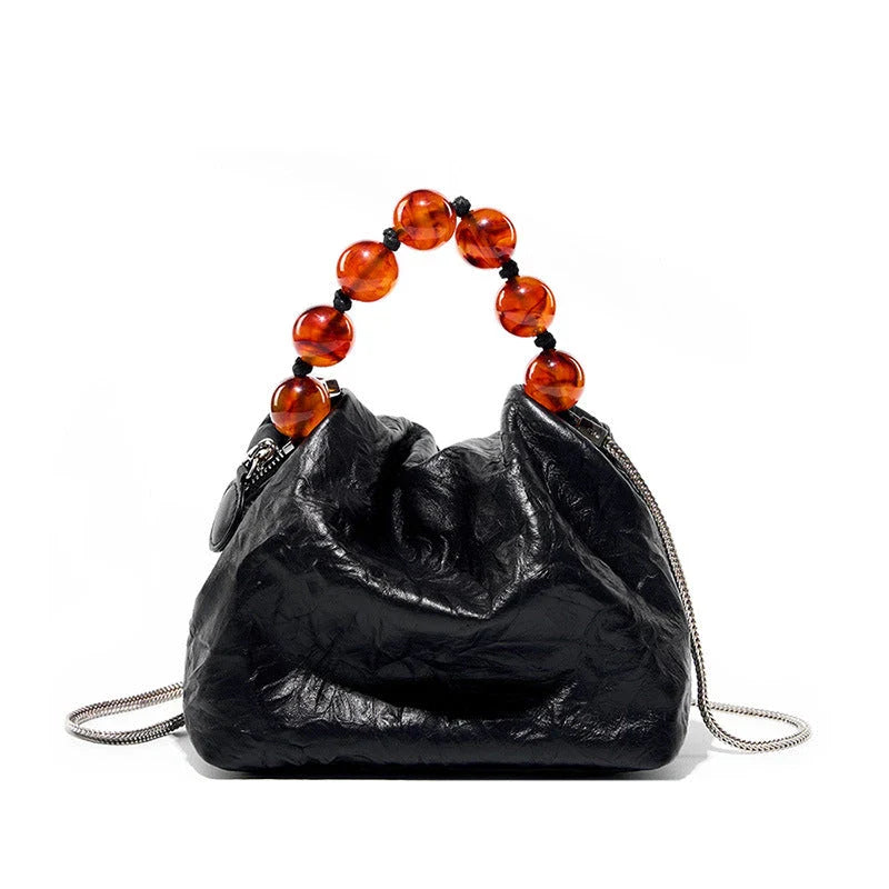 Premium leather crossbody bag with intricate beadwork, featuring a classic saddle shape and adjustable shoulder straps for versatile and secure everyday use.