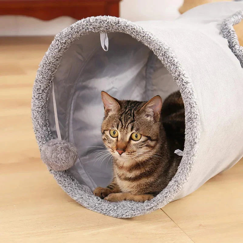 A collapsible cat tunnel made of crinkle suede with a peek-a-boo hole and dangling ball, providing a stimulating and entertaining play experience for cats.