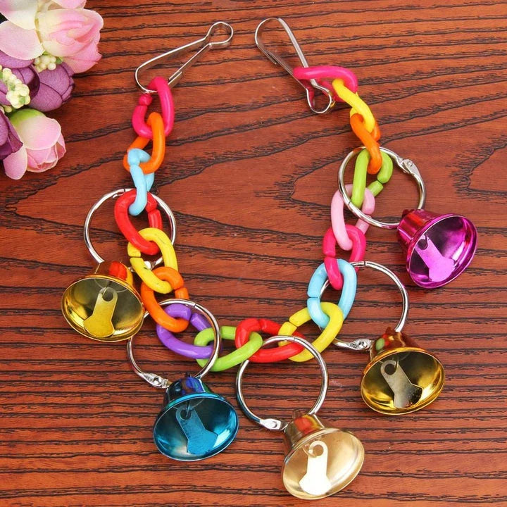 Acrylic bird bells swing with intricate design, hanging in a lush garden setting