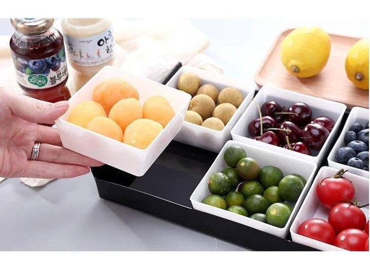 Premium British plastic snack trays in a variety of colours, including clear, white, and grey, with a black, white, or natural wood pallet for storage and display.