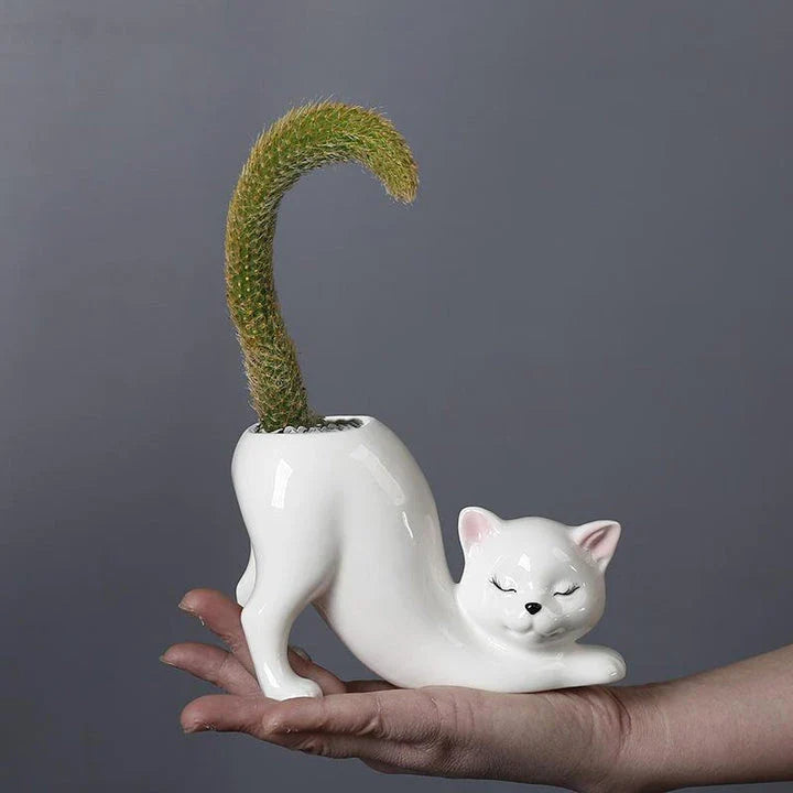 A white ceramic flower pot with a playful cartoon cat design and a functional tail element, perfect for desktops and small spaces.