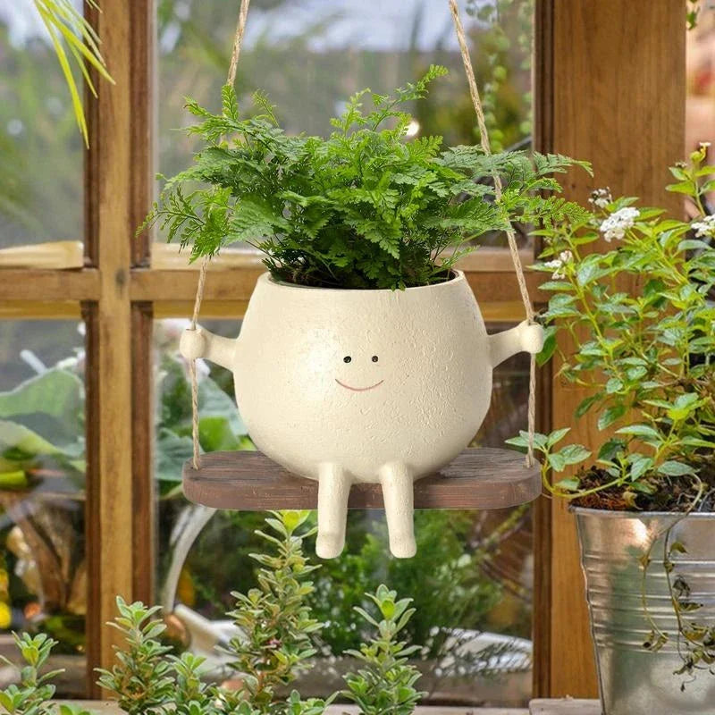 A white hanging planter with a charming, smiling child's face design, perfect for indoor or outdoor use.
