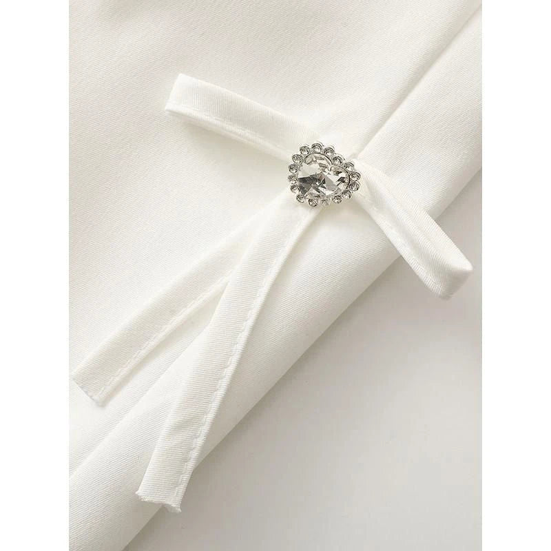 Stylish women's white blazer with a sparkling diamond bow accent, designed for fashion-forward British women