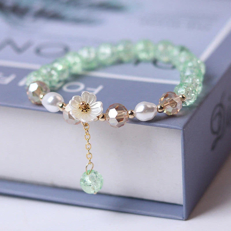 Elegant beaded bracelet with a white flower charm, vibrant purple crystal beads, and an adjustable design for a comfortable fit