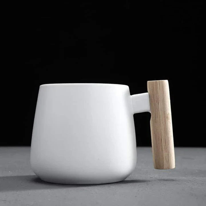 A stylish ceramic coffee mug with a colour block design and a coordinating wooden spoon