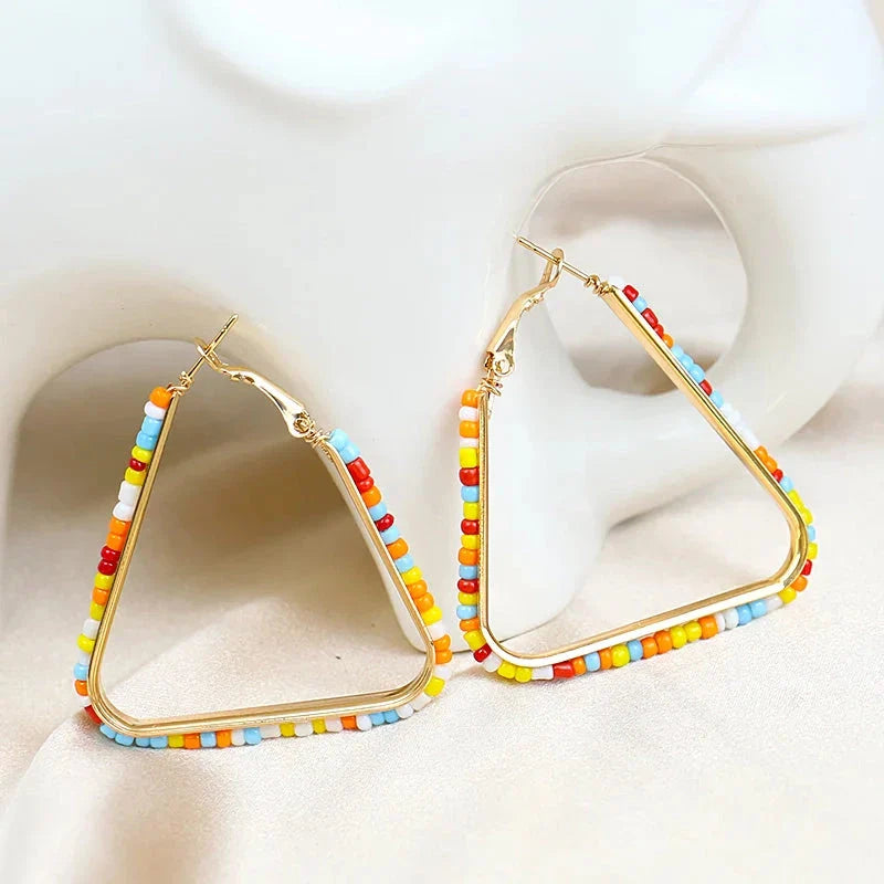 Colourful beaded triangle hoop earrings in gold metal with vibrant beadwork