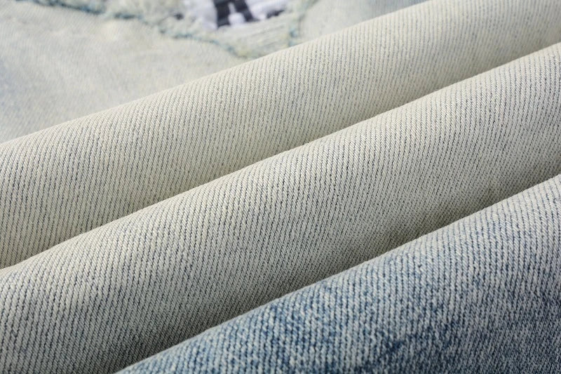 Stylish ripped denim jeans with a unique black and white patch design, perfect for British gentlemen