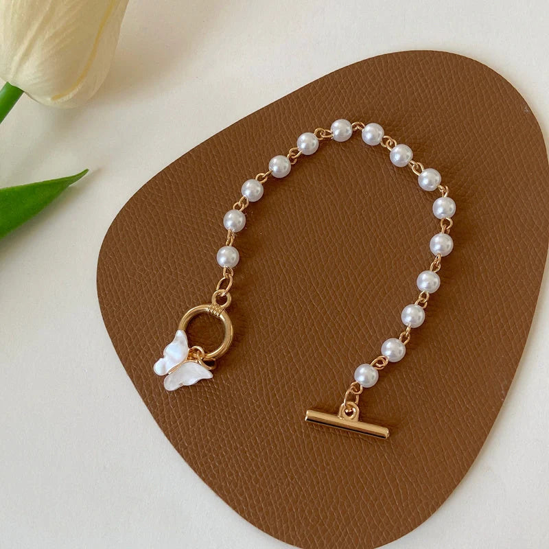 Gold charm chain bracelet with pearl and butterfly design for women