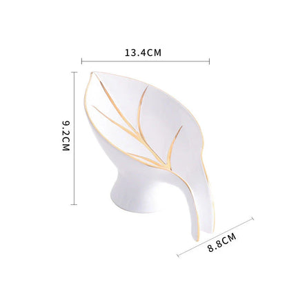 Elegant ceramic soap dish with leaf-shaped design, suction cup base, and drainage holes for bathroom storage and decor