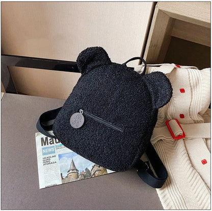 Adorable bear-shaped backpack made of soft fleece material in various colors, featuring a spacious main compartment and adjustable shoulder straps for comfortable wear.