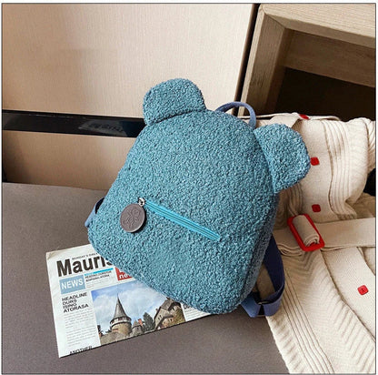 Adorable bear-shaped backpack made of soft fleece material in various colors, featuring a spacious main compartment and adjustable shoulder straps for comfortable wear.