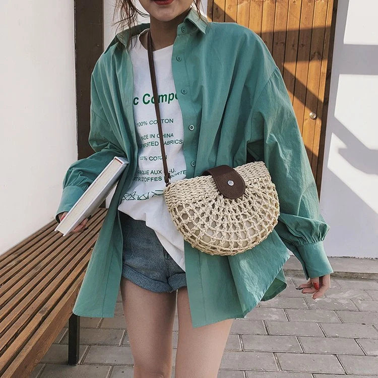 A stylish one-shoulder straw saddle bag with a zipper closure, perfect for modern British consumers.
