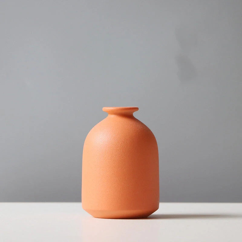 Ceramic vase in various colours, including brown, black, green, and orange, showcasing a minimalist Scandinavian design that is perfect for living room decor.