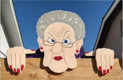 Quirky garden fence art decoration featuring an elderly couple peeking over a fence