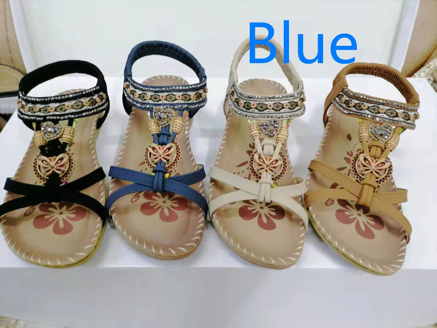 Women's flat sandals with flower rhinestone detail in black, royal blue, apricot, and brown