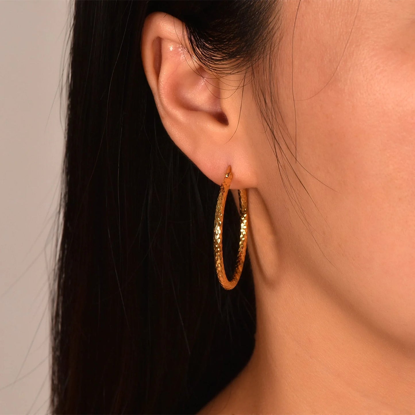 Elegant 18K gold-plated round ring earrings with embossed detail, perfect for any occasion.