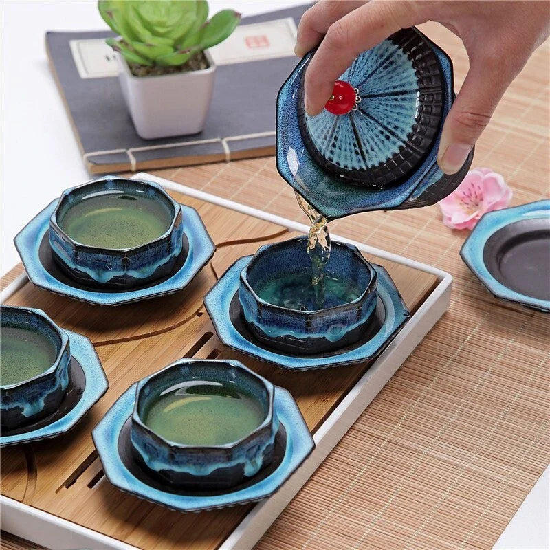 A beautiful porcelain tea set with a pagoda design, including a teapot, cups, trays, and a carrying bag for easy portability.