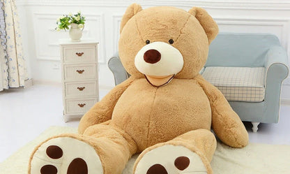 Colossal plush teddy bear in various sizes and colors, including light brown, dark brown, gray, white, pink, and purple